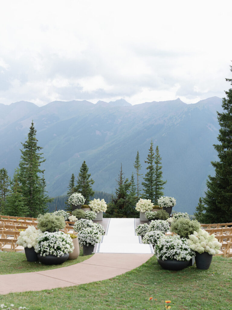Mountain wedding ceremony design with white floral arrangements and scenic alpine views event designer HMR Designs