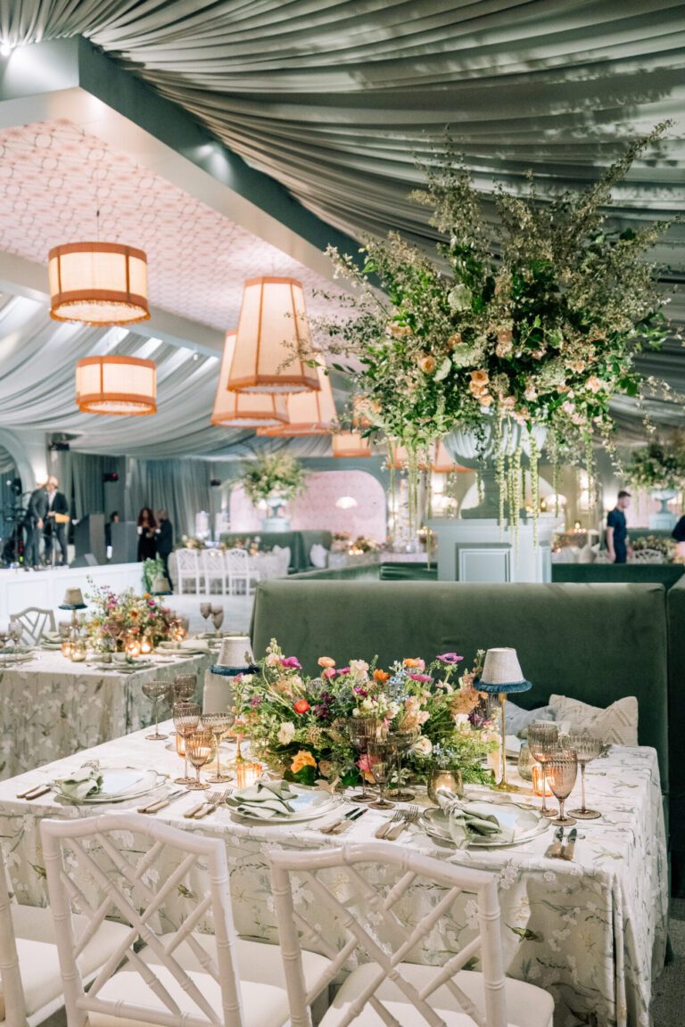 Tented Midwest wedding design reception with greenery, pendant lights and colorful floral centerpieces wedding planning Rishi Patel