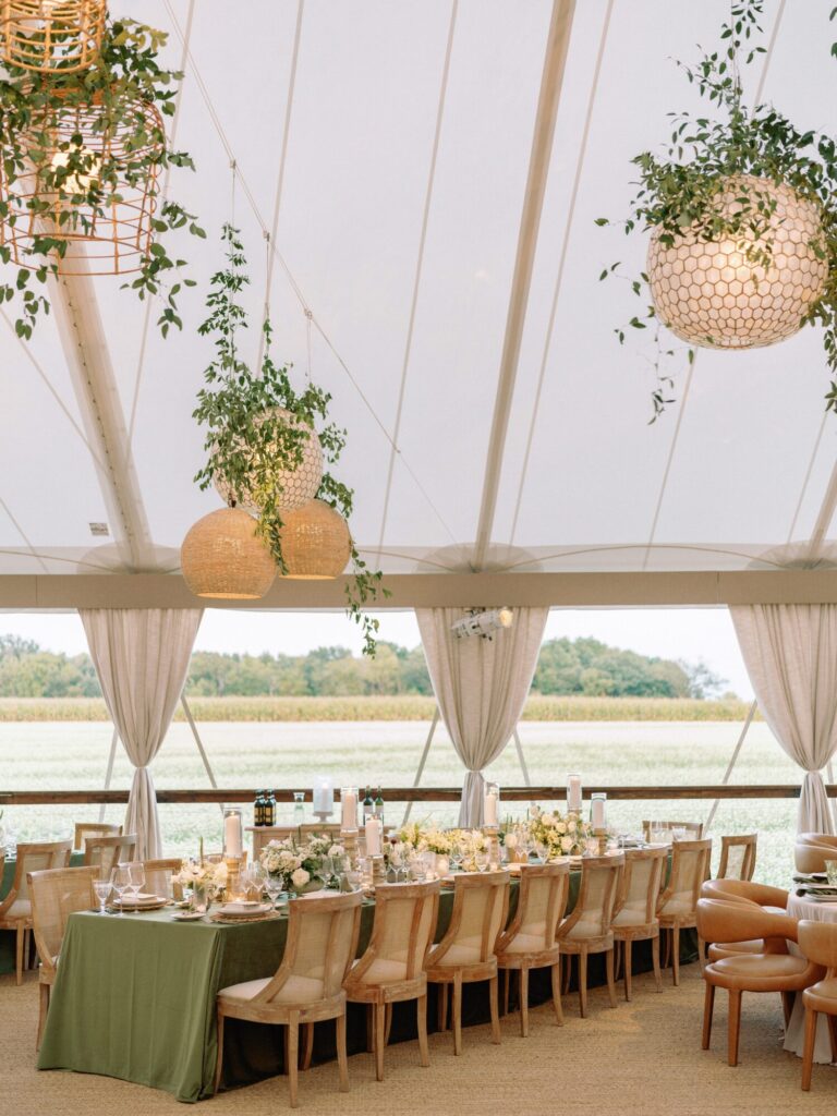 MIdwest wedding design reception table beneath a tent with hanging greenery and lanterns wedding designer HMR Designs