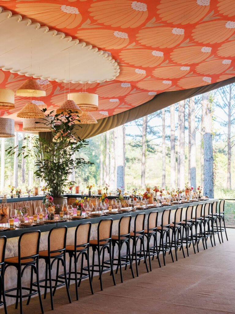 Tented Midwest wedding reception design and decor with bold orange patterned ceiling and long bar seating by Rishi the Designer