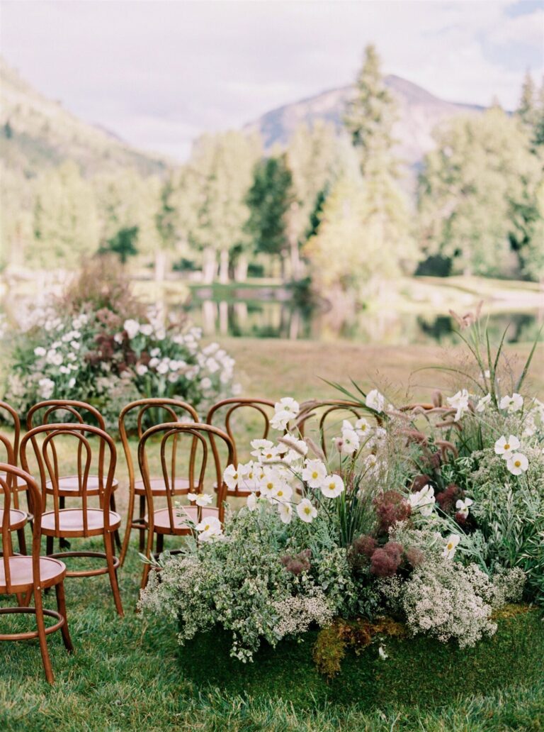Outdoor wedding design ceremony with wooden chairs, white florals and mountain views wedding decor Rishi the Designer