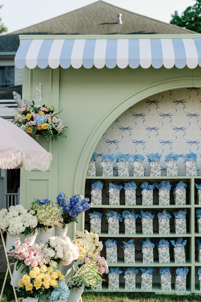 Pastel wedding design event display with striped awning, floral arrangements and custom favors