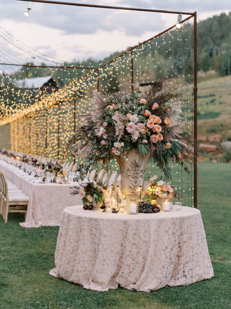 Outdoor wedding design escort card table with pink florals beneath a suspended string-light installation wedding planning Rishi the Designer