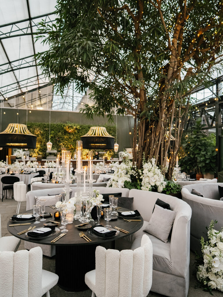 Chicago wedding designer greenhouse reception with mature trees, black dining tables and white floral arrangements