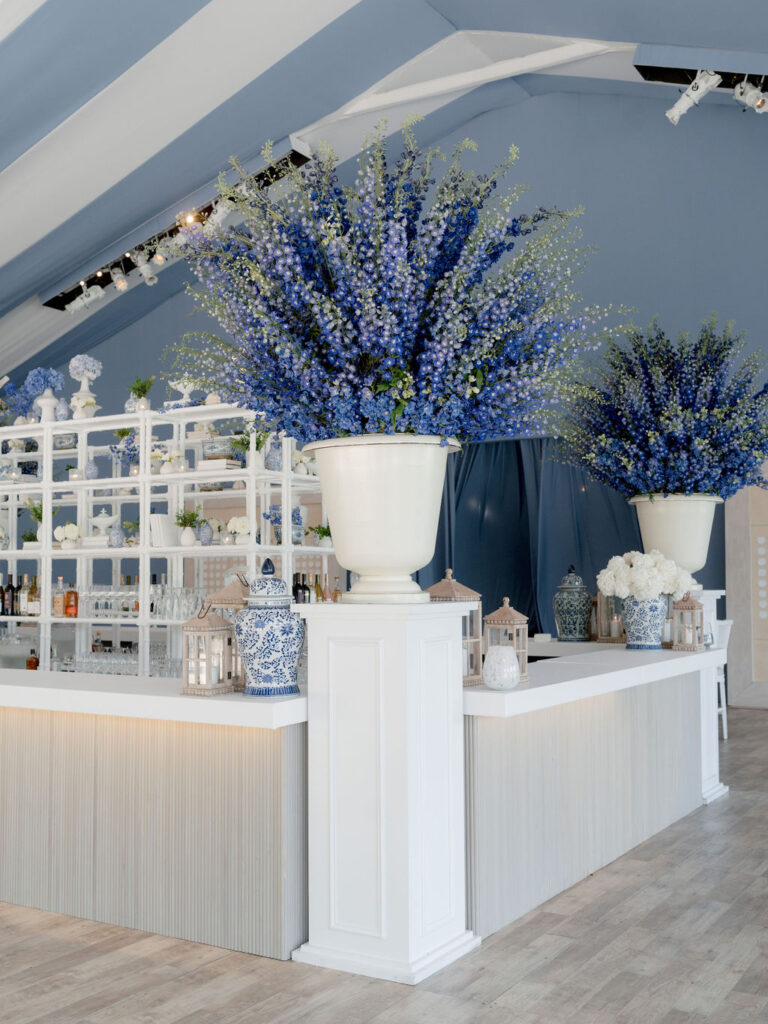Chicago wedding designer, white event bar with blue floral arrangements and decorative display shelving planner Rishi the Designer at HMR Designs