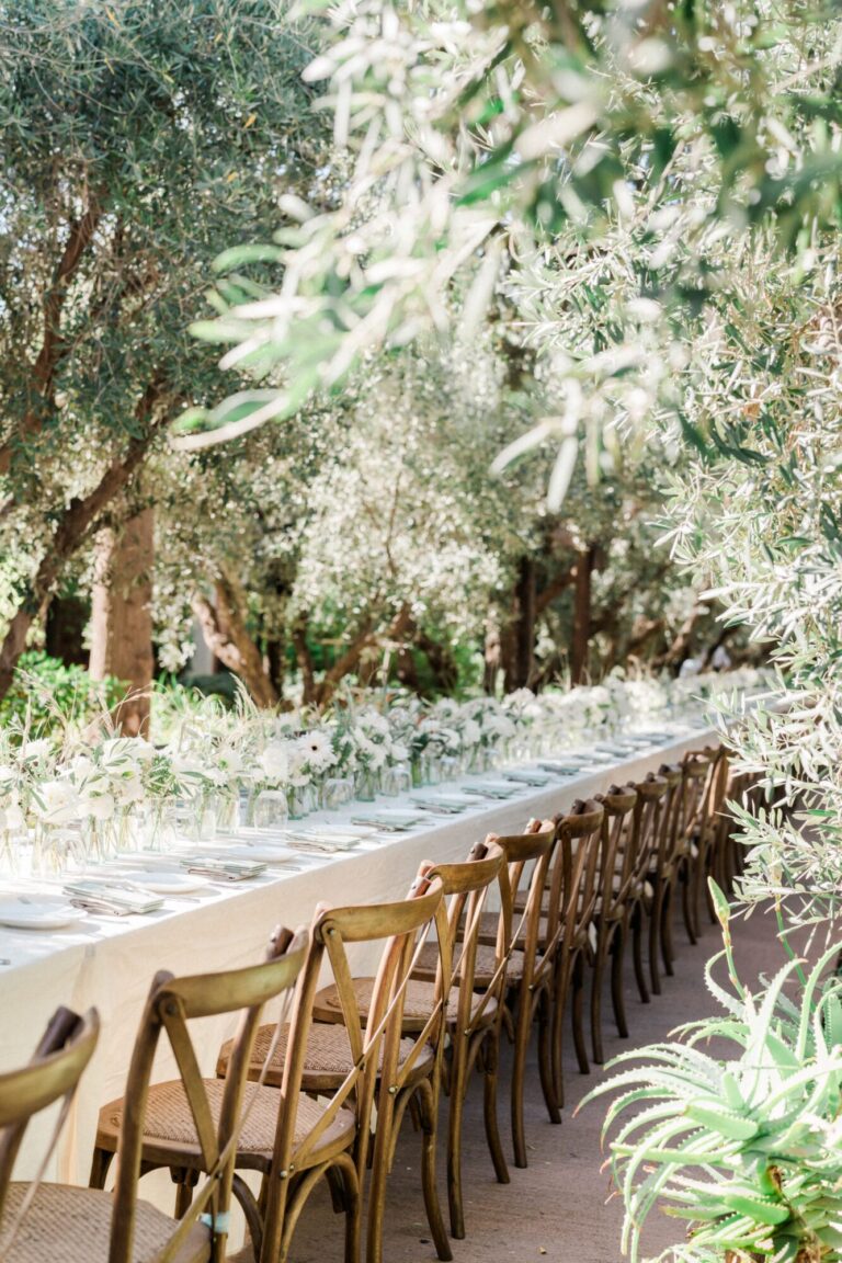 Outdoor wedding design dinner reception with long table beneath trees and surrounding greenery designer Rishi Patel