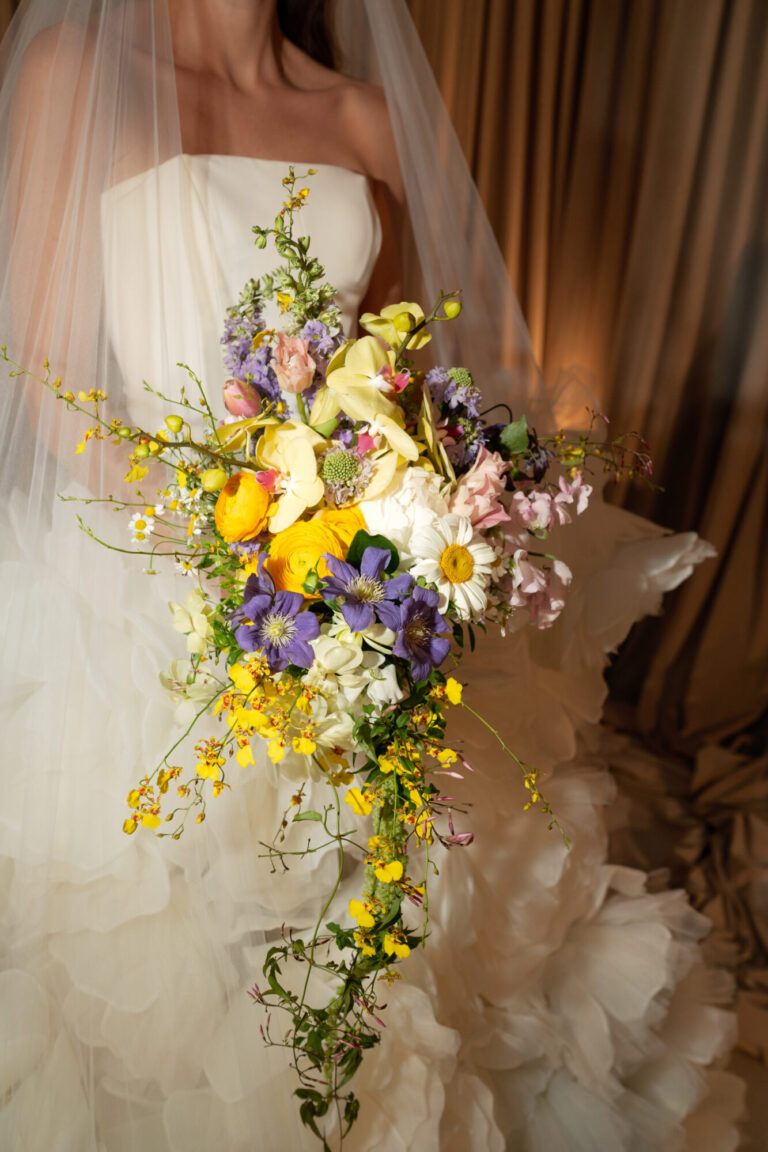 Wedding florist Daisy Foko Granson bride holding a bouquet with yellow, purple and white flowers designer HMR Designs