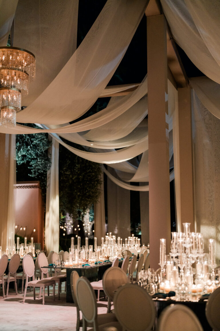 Formal wedding reception design with sweeping ceiling draping, chandeliers and candlelit tables by Rishi the Designer