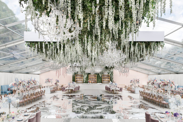 A wisteria studded ceiling installation hangs over a stunning mirrored dance floor surrounded by long pink tables at this reception.