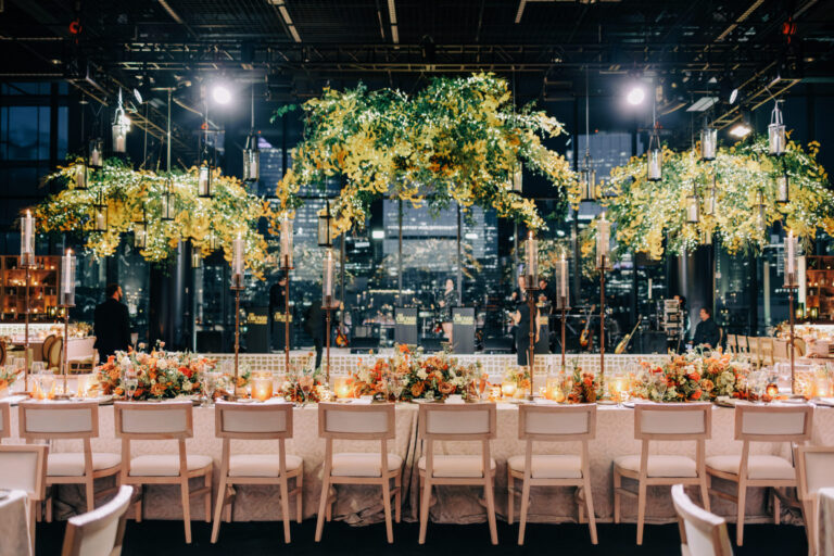 Luxury Chicago wedding reception head table with tall golden floral tree centerpieces, orange and rust floral arrangements, and city skyline views