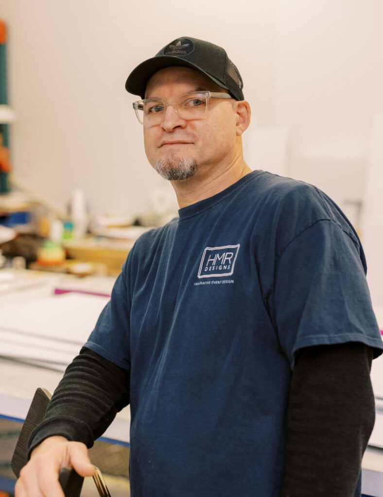 Edwin Torres, Art Production at HMR Designs, smiling in the workshop