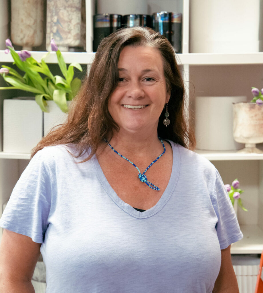 Susie Blair, Daily Order Floral Designer at HMR Designs, smiling in front of florals