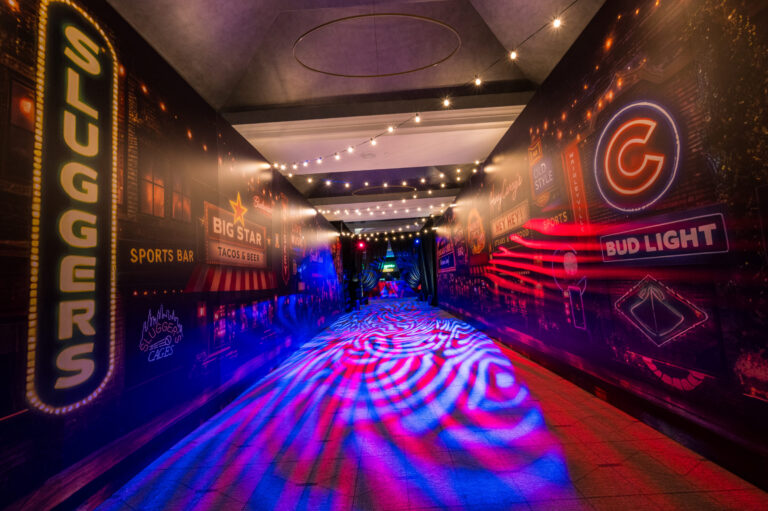 Wrigleyville themed event entrance corridor at Bryn Mawr Country Club with custom wall wraps, string lights, and projected floor lighting