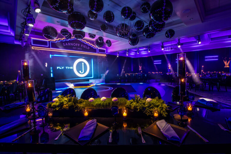 Baseball themed Bar Mitzvah reception at Bryn Mawr Country Club with purple uplighting, hanging black mirror balls, and LED monogram stage