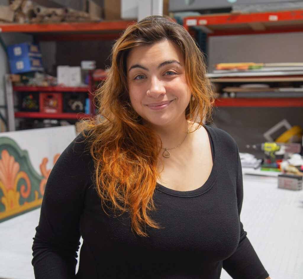 Caro Arana, Art Production Manager at HMR Designs, smiling in the workshop