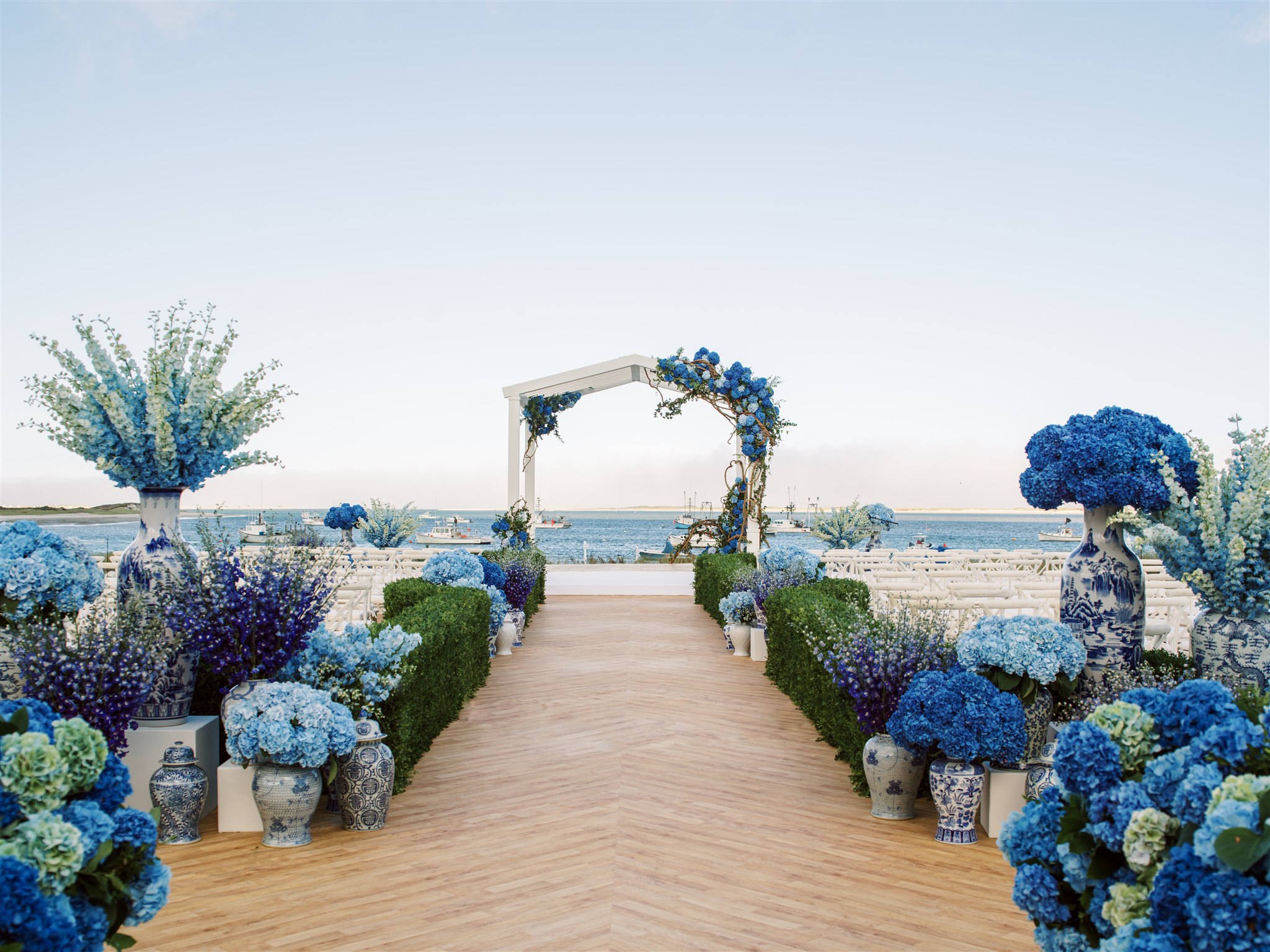 Waterfront wedding ceremony with blue hydrangeas and floral arch by Rishi Patel